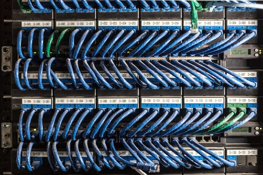 Patch panel com cabos de rede azuis organizados e pontos identificados por etiquetas