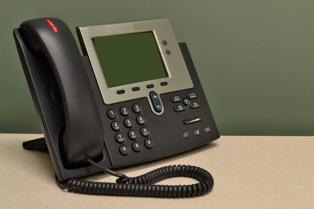 Telefone IP com tela e teclado sobre uma mesa de escritório